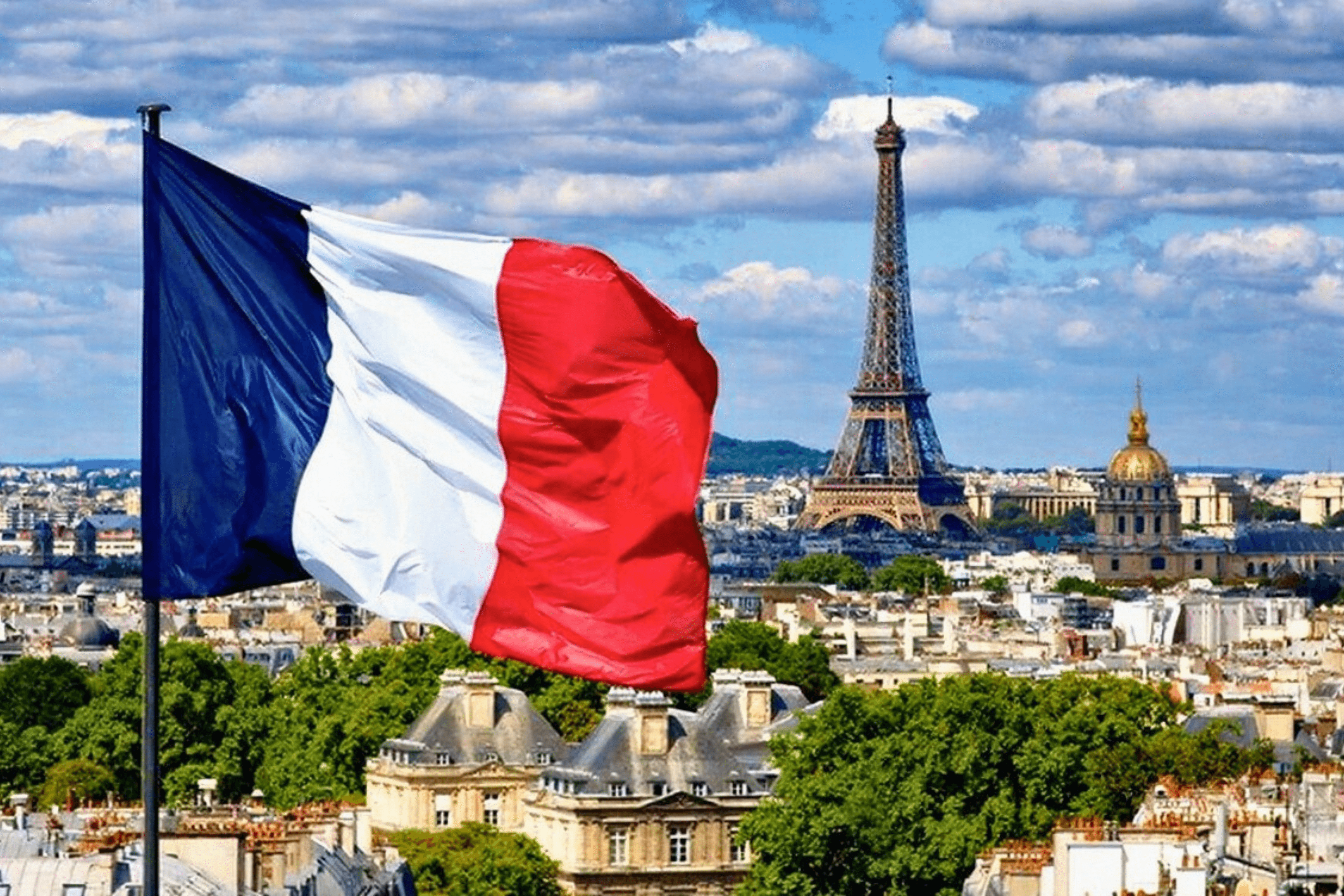 The national flag of France flies high in the skyline of Paris, where the Eiffel Tower can be seen in the background